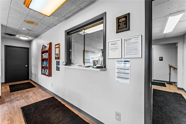 a hallway with painting on the wall and a wooden floor