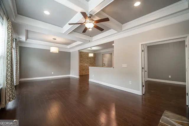 an empty room with wooden floor and a hallway