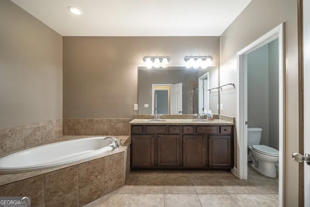 a bathroom with a granite countertop bathtub a sink and a mirror