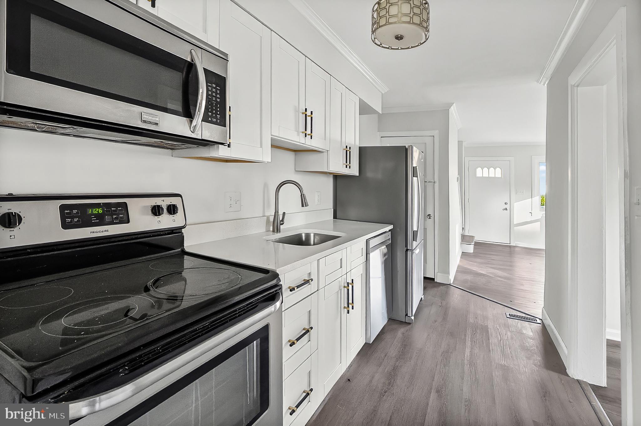 30 North Athol Avenue Baltimore, MD 21229 - Photo 6 of 20 a kitchen with stainless steel appliances a stove a microwave and a hard wood floor