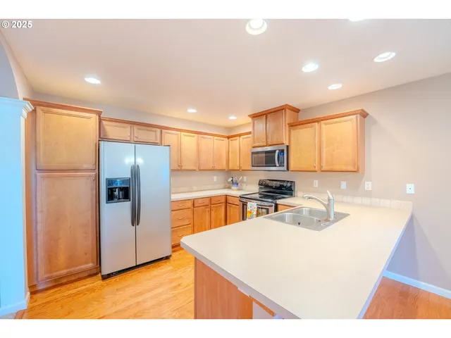 a kitchen with stainless steel appliances granite countertop a refrigerator a sink and a stove