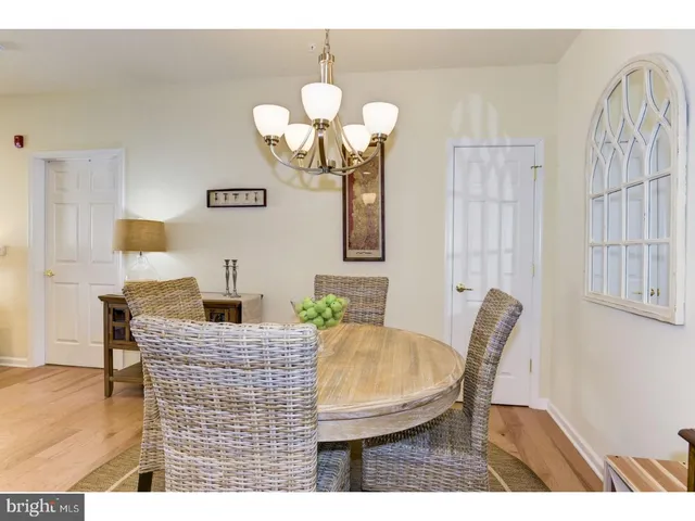 a dining room with wooden floor a chandelier a wooden table and chairs