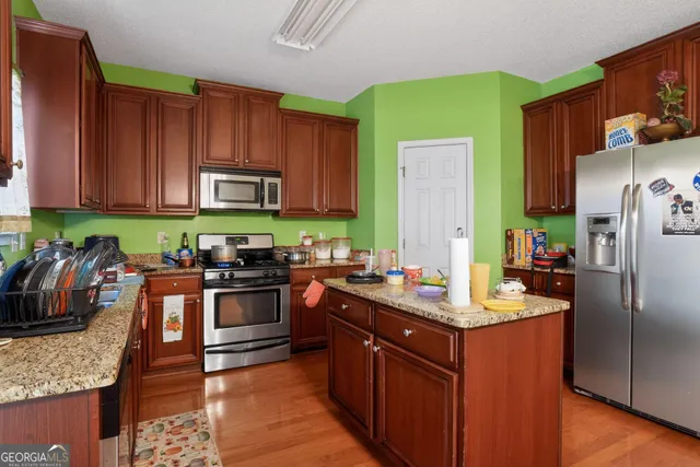 a kitchen with kitchen island granite countertop a sink stove and refrigerator