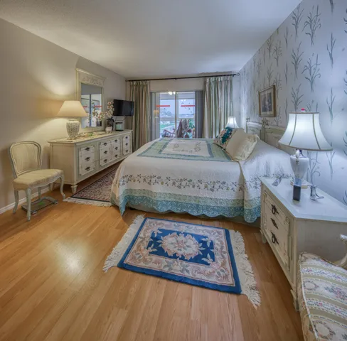 a spacious bedroom with a bed a dresser and wooden floor