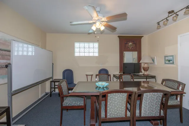 a room with pool table a table and windows