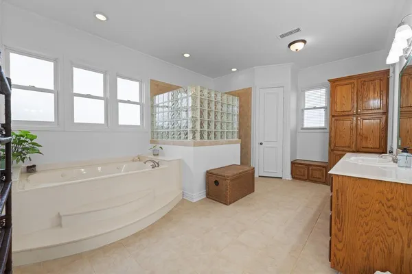 a large white kitchen with a large tub and chandelier
