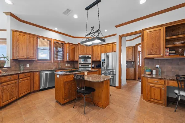 a kitchen with stainless steel appliances granite countertop a stove top oven a sink dishwasher a dining table and chairs with wooden floor