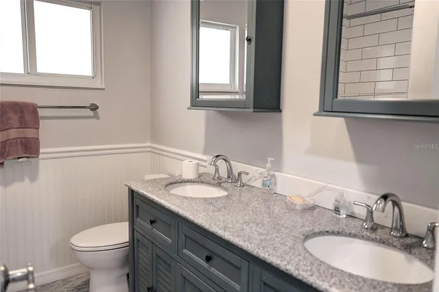 a bathroom with a granite countertop toilet sink and mirror
