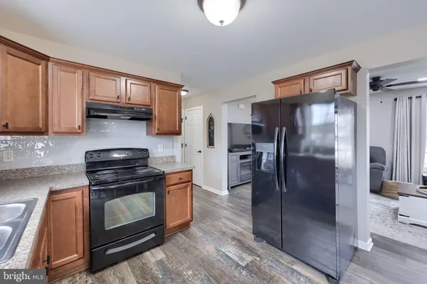 a kitchen with stainless steel appliances granite countertop a refrigerator a stove and a sink with wooden floors