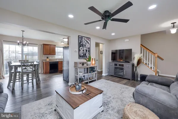 a living room with furniture kitchen view and a wooden floor