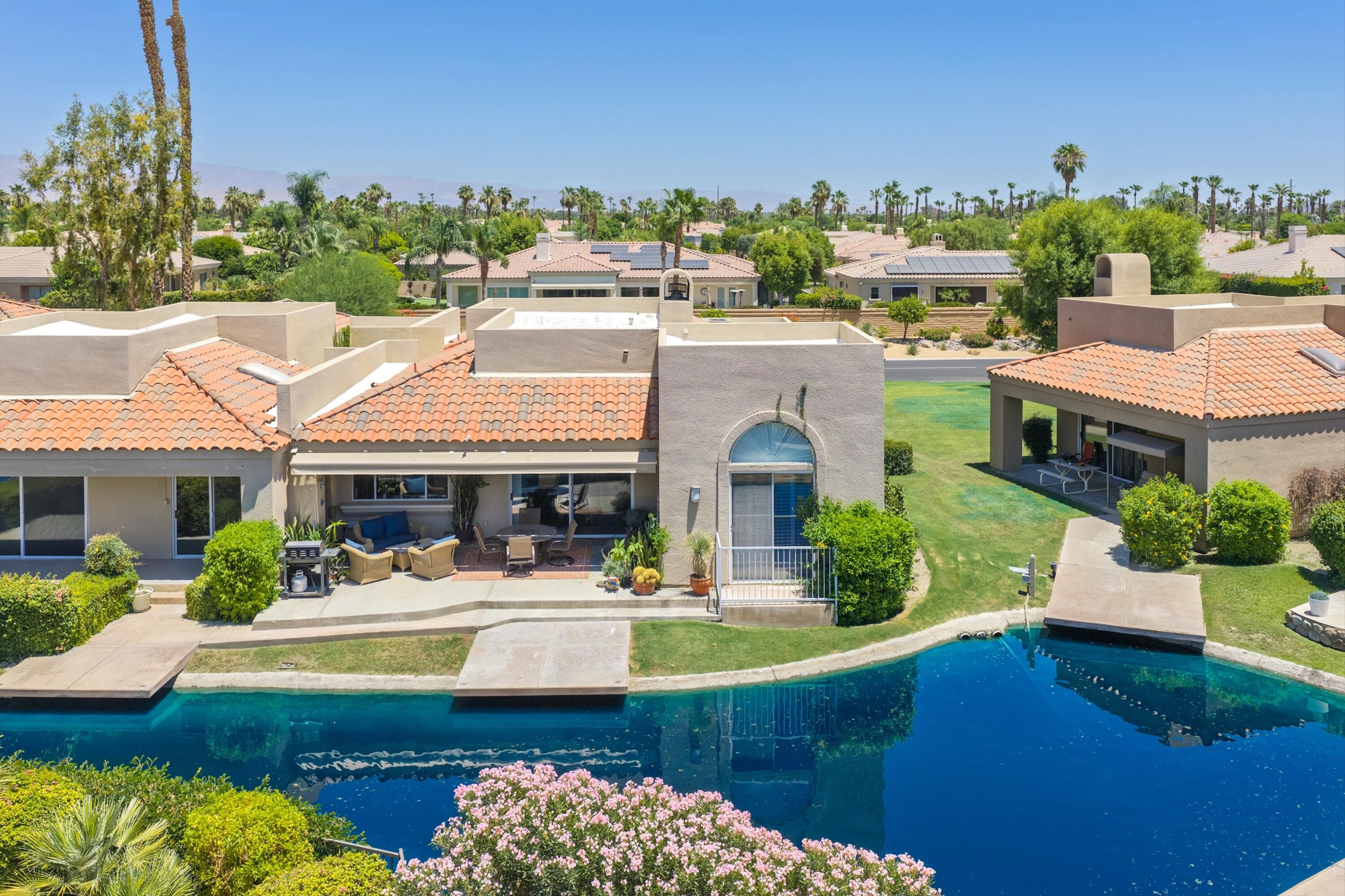 138 Lakeshore Drive Rancho Mirage, CA 92270 - Photo 26 of 30 a view of a house with pool lawn chairs and a dining table under an umbrella