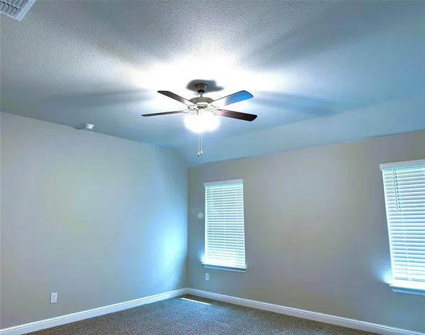 an empty room with window and chandelier fan