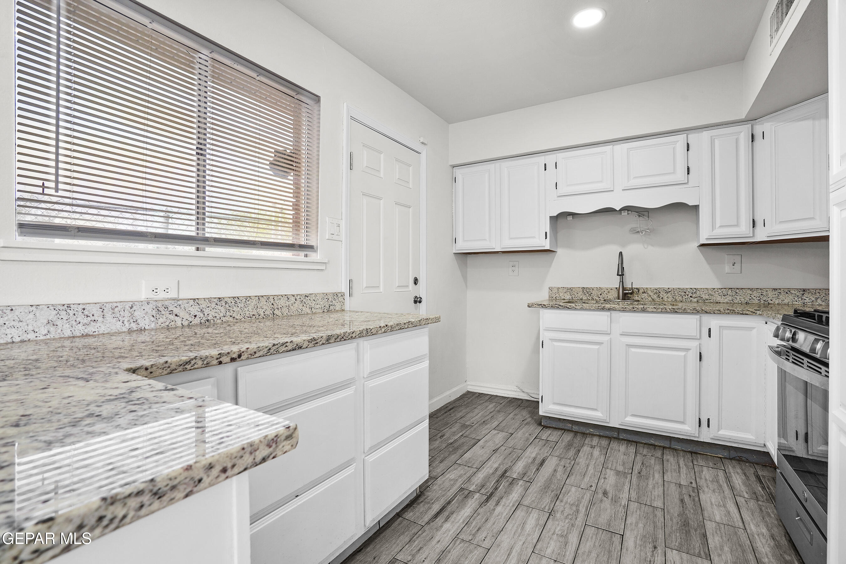 7809 Hemlock Street El Paso, TX 79925 - Photo 11 of 32 a kitchen with granite countertop wooden cabinets and white appliances