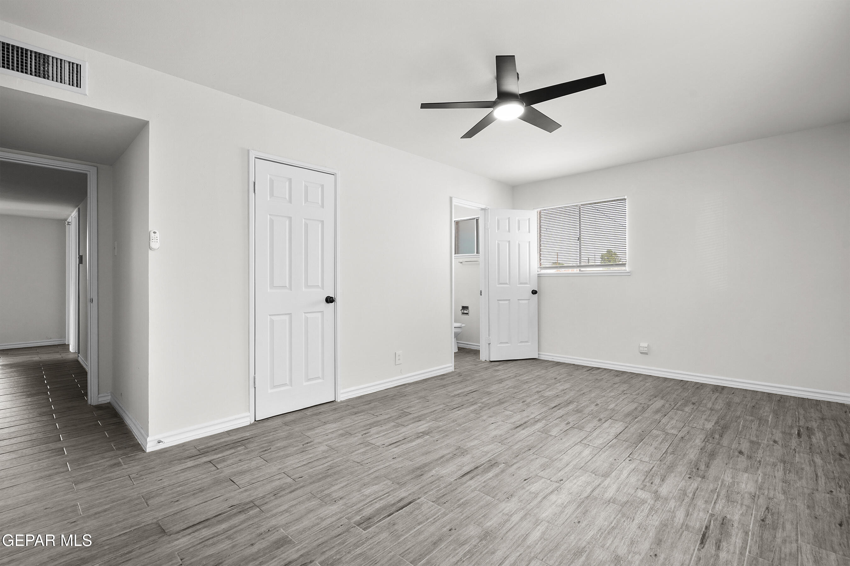 7809 Hemlock Street El Paso, TX 79925 - Photo 23 of 32 an empty room to hallway with wooden floor wooden door and a ceiling fan