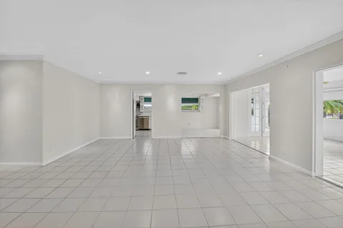 a view of an empty room with a window and kitchen view