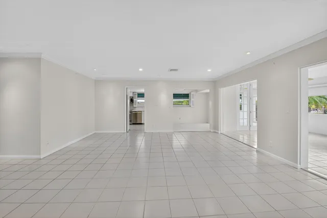 a view of an empty room with a window and kitchen view