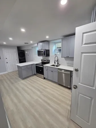 a large kitchen with a sink stainless steel appliances and cabinets