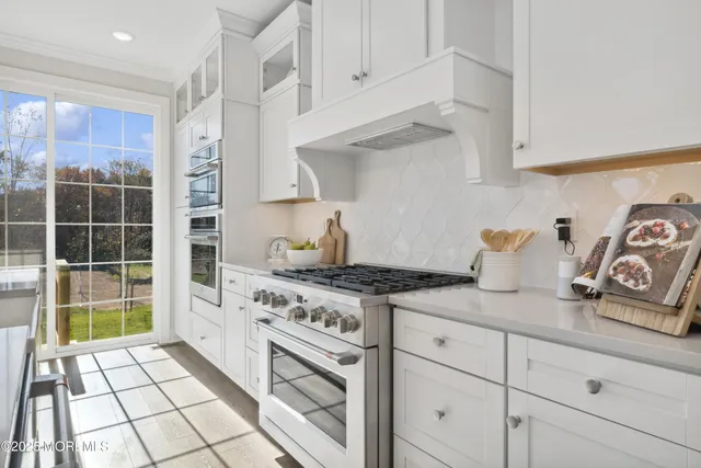 a kitchen with granite countertop a stove a sink and white cabinets
