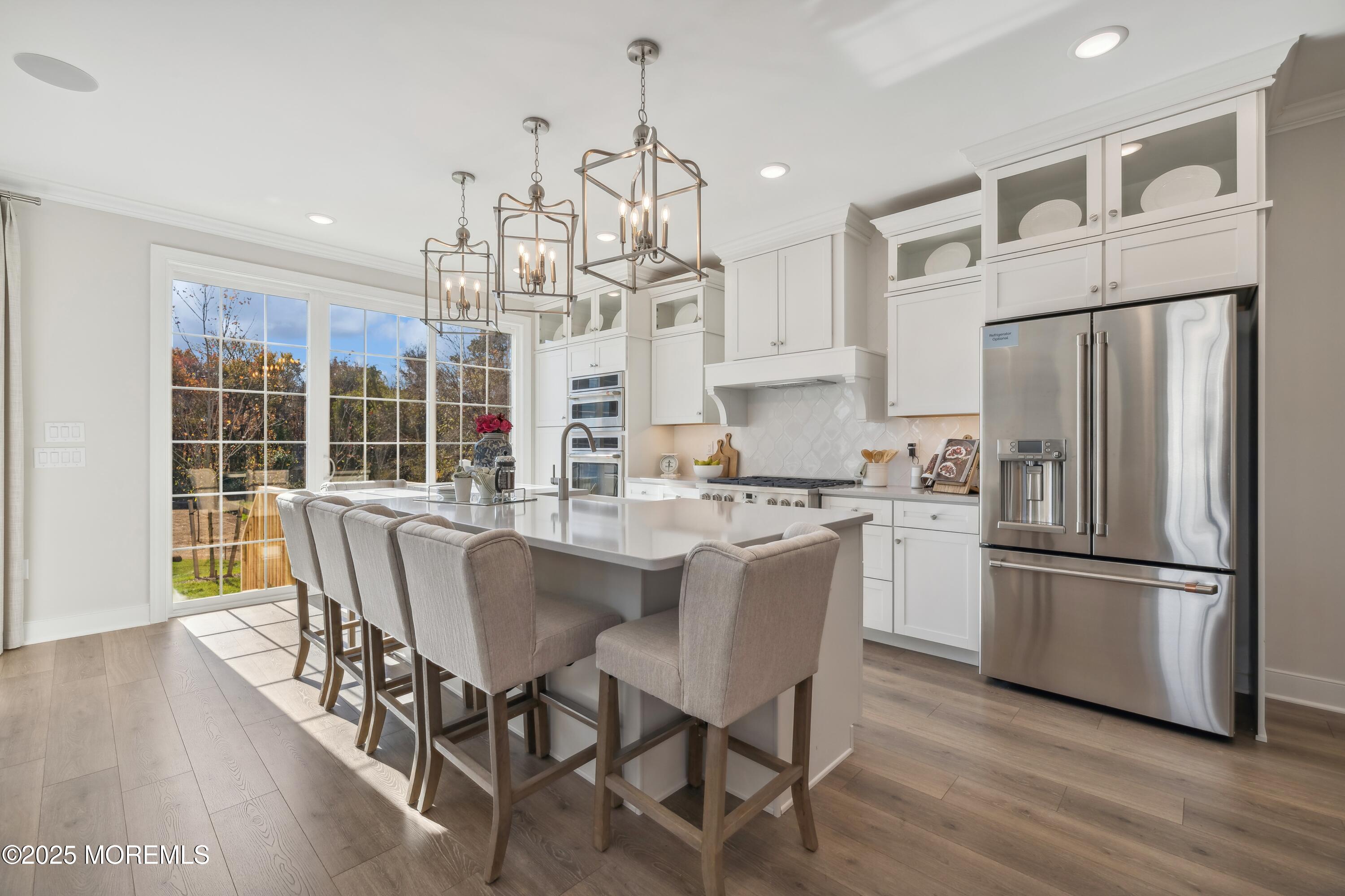 4061 Heron Drive Farmingdale, NJ 07727 - Photo 9 of 36 a kitchen with stainless steel appliances granite countertop a dining table chairs refrigerator and wooden floor