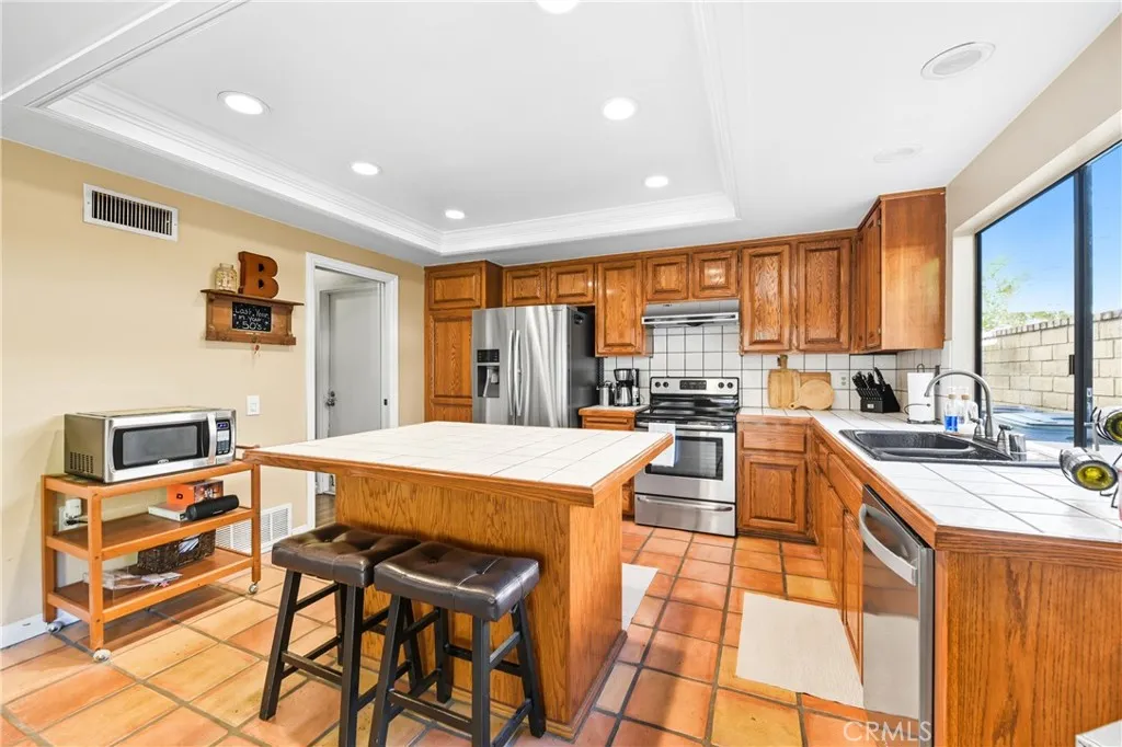 21902 Raintree Lane Lake Forest, CA 92630 - Photo 11 of 46 a kitchen with stainless steel appliances granite countertop a stove top oven a sink dishwasher and white cabinets with wooden floor