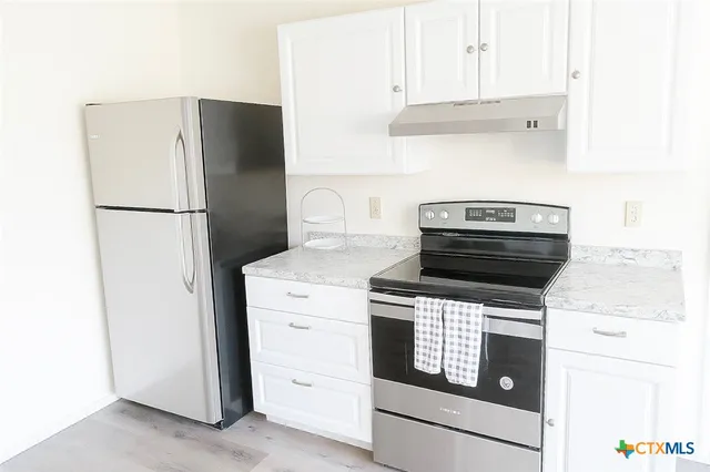a kitchen with a stove refrigerator and white cabinets
