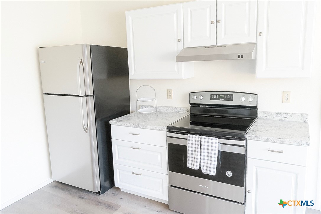 1054 Rolling Path New Braunfels, TX 78130 - Photo 2 of 14 a kitchen with a stove refrigerator and white cabinets