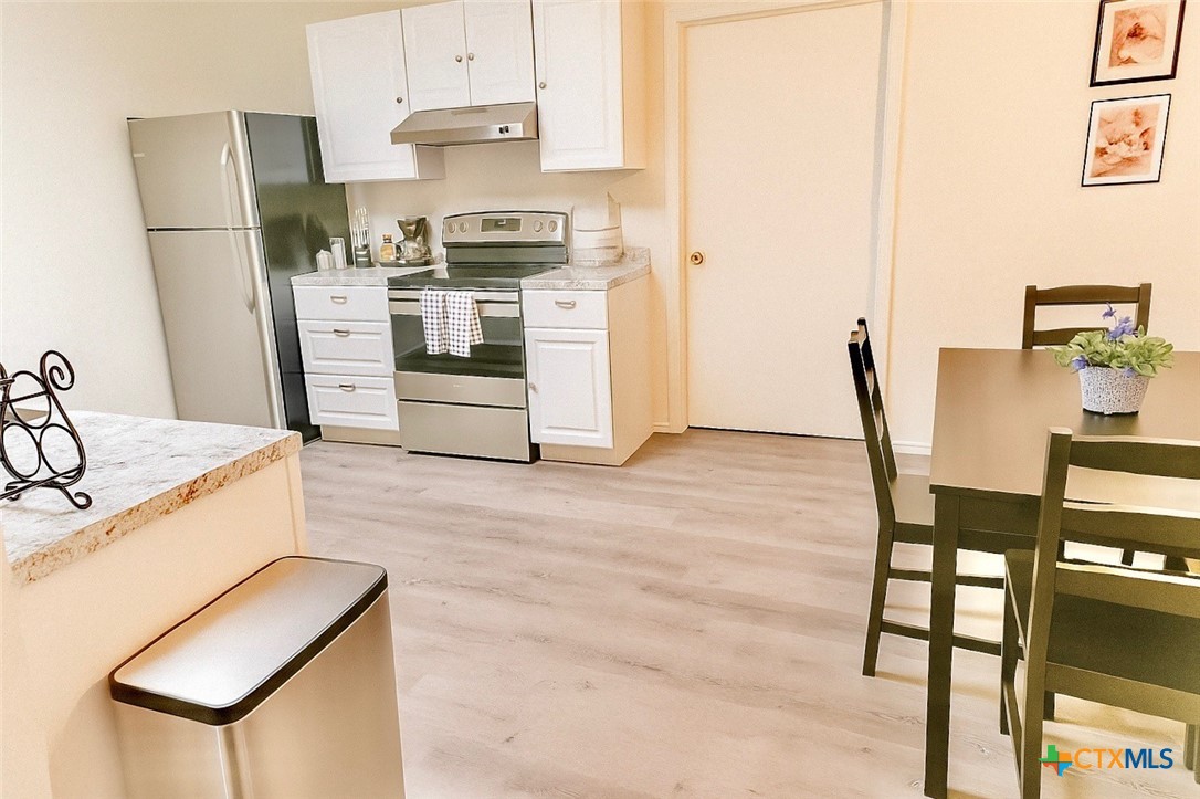 1054 Rolling Path New Braunfels, TX 78130 - Photo 3 of 14 a kitchen with stainless steel appliances granite countertop a stove a refrigerator a dining table and chairs