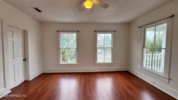 an empty room with wooden floor and windows