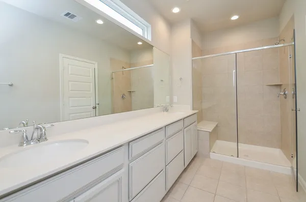 a spacious bathroom with a shower a sink and a mirror
