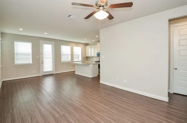 a view of an empty room with window and wooden floor