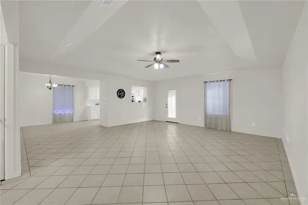 a view of an empty room and chandelier fan