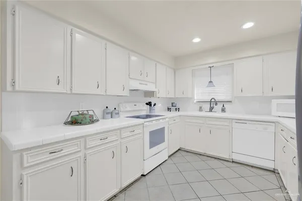 a kitchen with white cabinets white appliances and sink