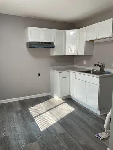 a kitchen with granite countertop a sink cabinets and wooden floor