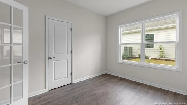 an empty room with wooden floor and windows