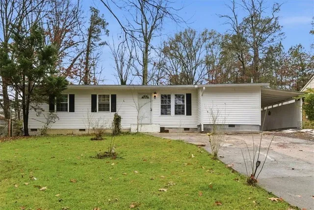 a front view of house with yard and trees in the background