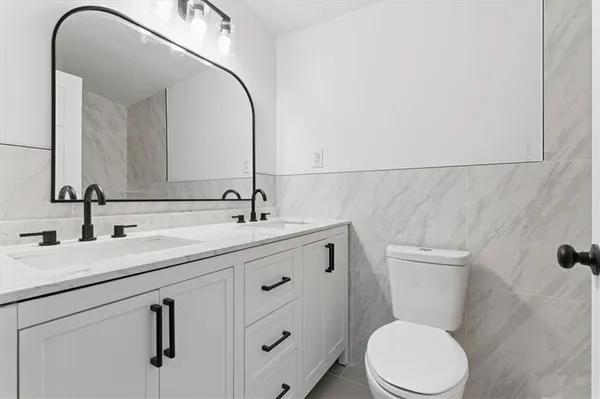 a bathroom with a granite countertop sink toilet and mirror