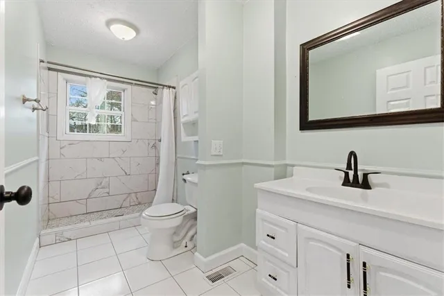 a bathroom with a granite countertop sink toilet and mirror