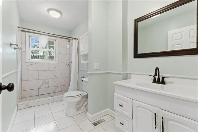 a bathroom with a granite countertop sink toilet and mirror