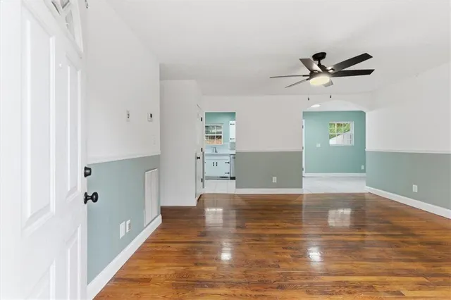 a view of a hallway with wooden floor and a ceiling fan