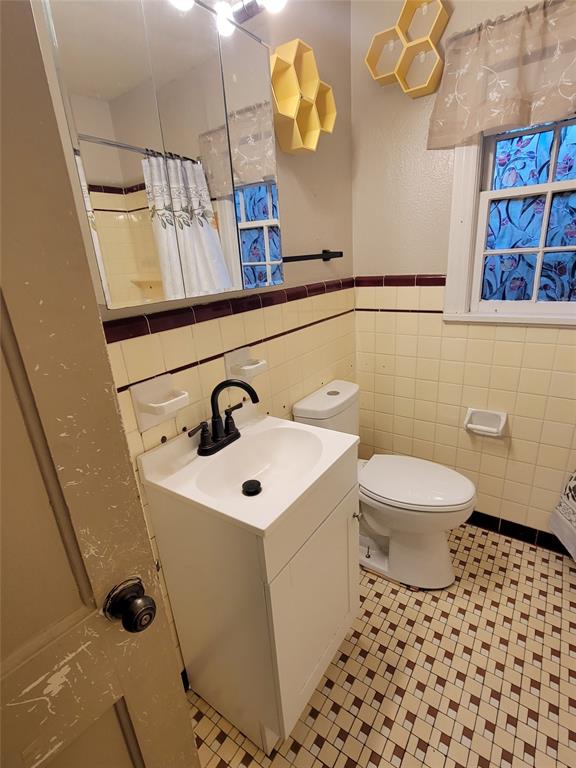 211 Wichita Street Shreveport, LA 71101 - Photo 6 of 10 Bathroom with vanity, a shower with shower curtain, light tile patterned floors, a wainscoted wall, and tile walls