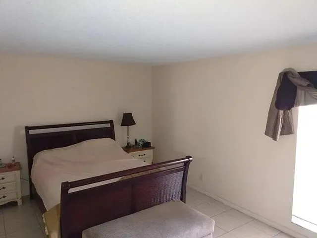 a bed sitting in a bedroom next to a window