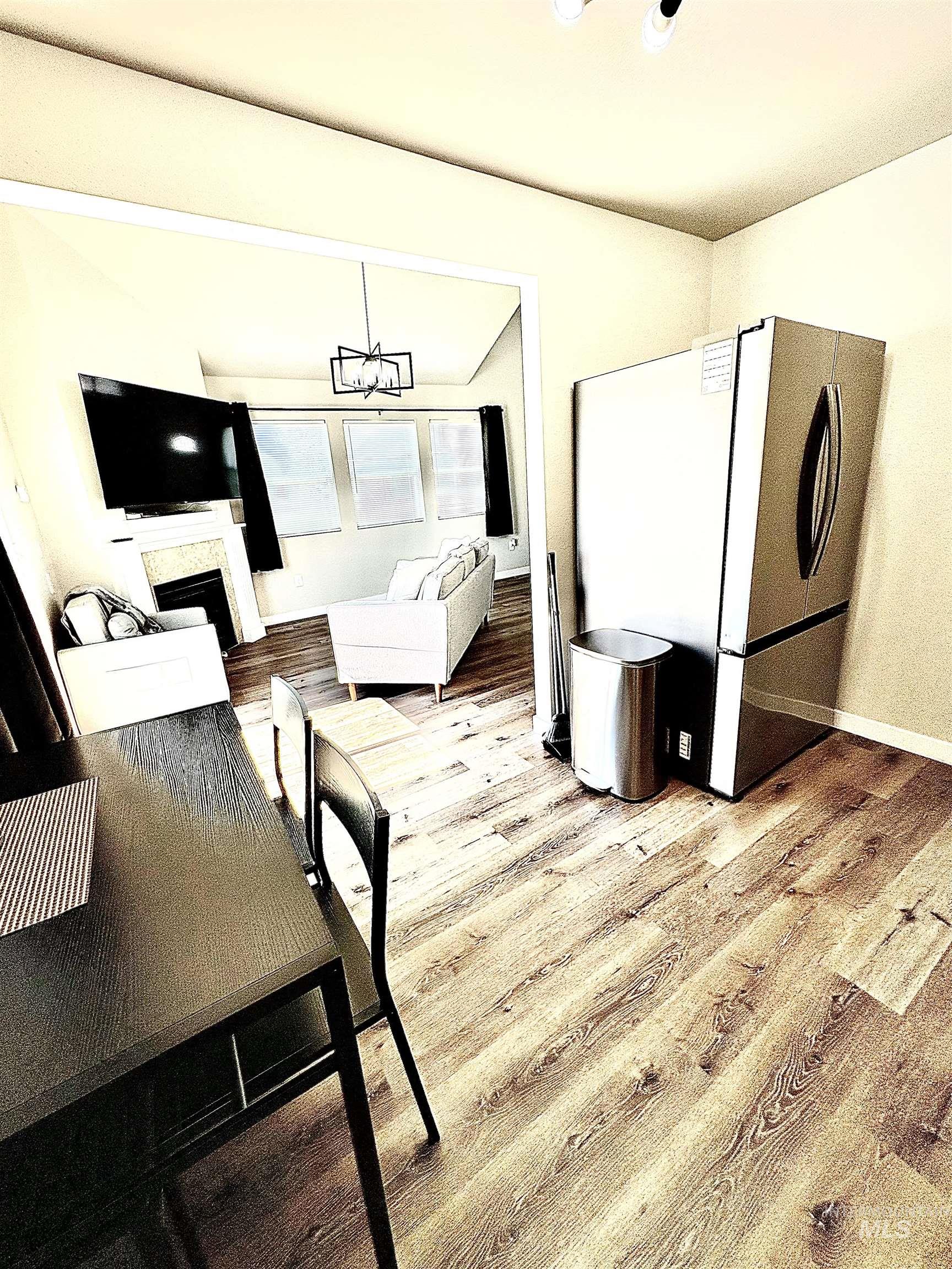 4802-4804 Maid Jessica Street Caldwell, ID 83607 - Photo 29 of 31 Dining room featuring a fireplace, light wood-style floors, and a chandelier