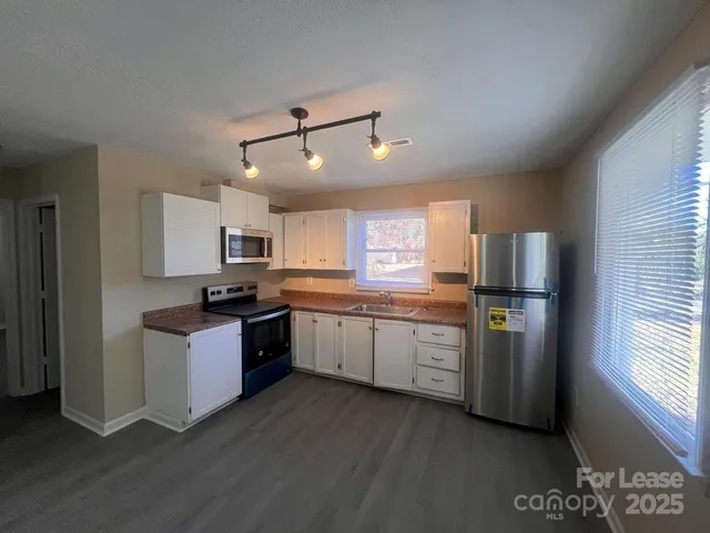 a kitchen with granite countertop a refrigerator stove top oven and sink