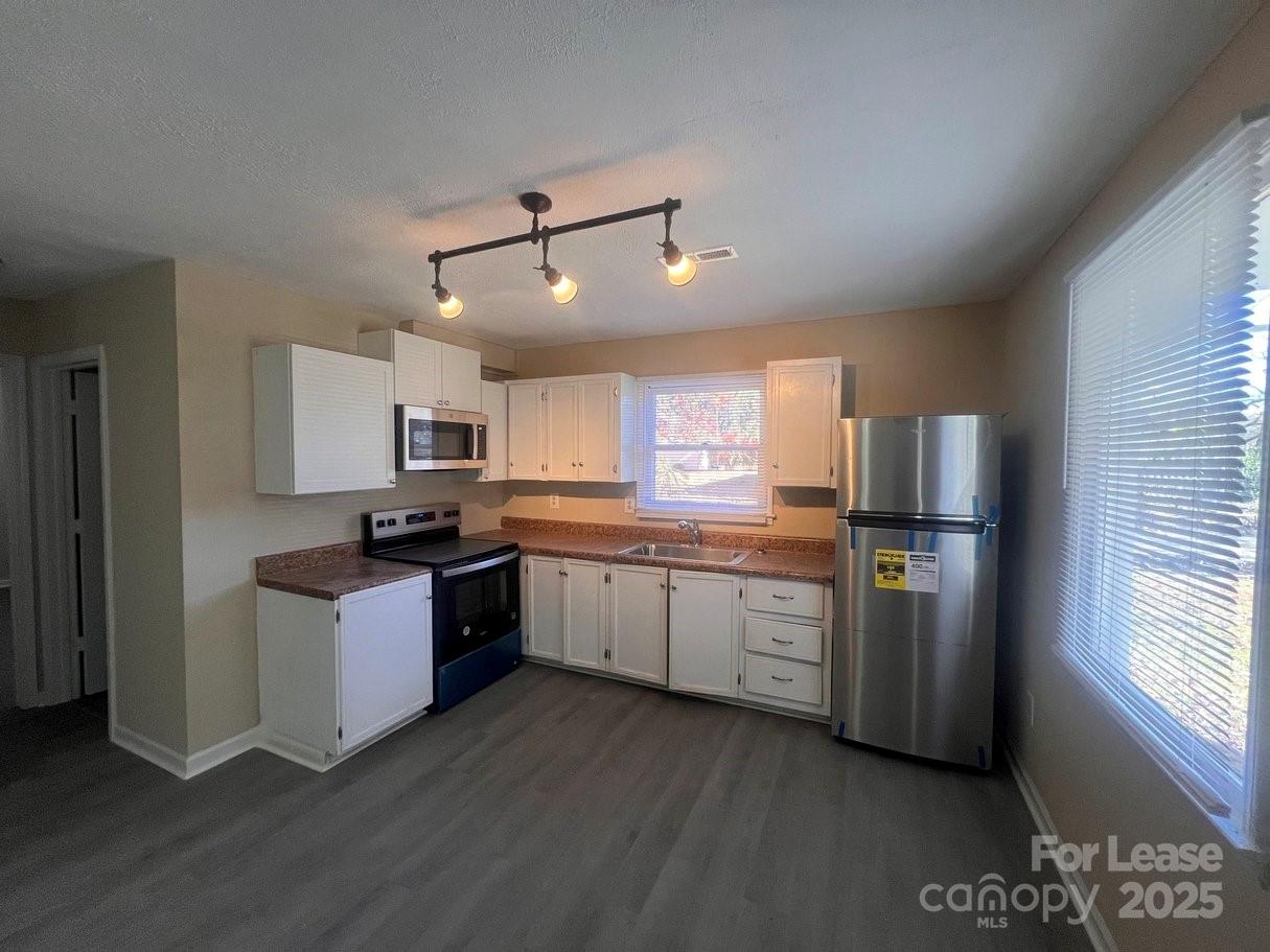 a kitchen with granite countertop a refrigerator stove top oven and sink