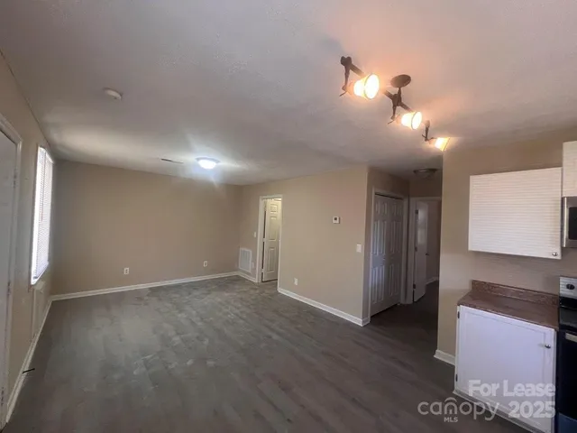 a view of an empty room with window and wooden floor