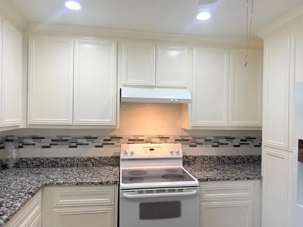 a kitchen with granite countertop cabinets sink and stove