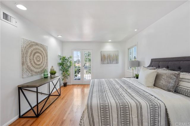 a bedroom with a bed a mirror on dresser and a wooden floor