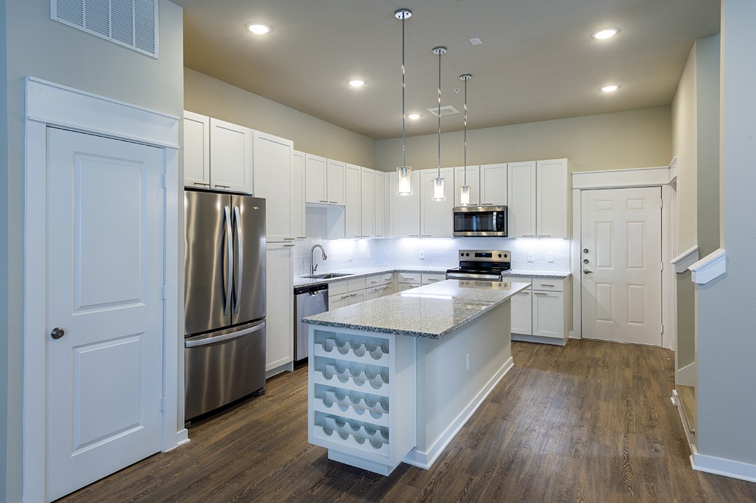 1724 Partnership Way, Unit 3101 Katy, TX 77449 - Photo 22 of 30 a large kitchen with stainless steel appliances granite countertop a refrigerator stove a sink and white cabinets with wooden floor