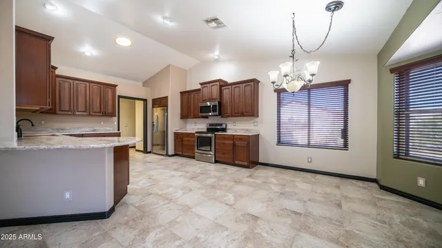 a large kitchen with kitchen island granite countertop a stove a sink a counter space and cabinets
