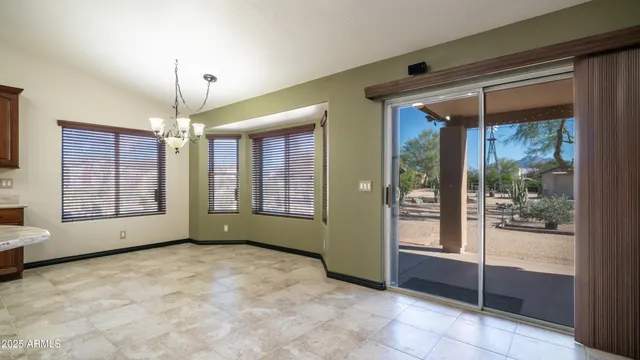 a view of an empty room with window and chandelier